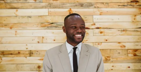 Portrait of a happy young african businessman over a wooden wall.