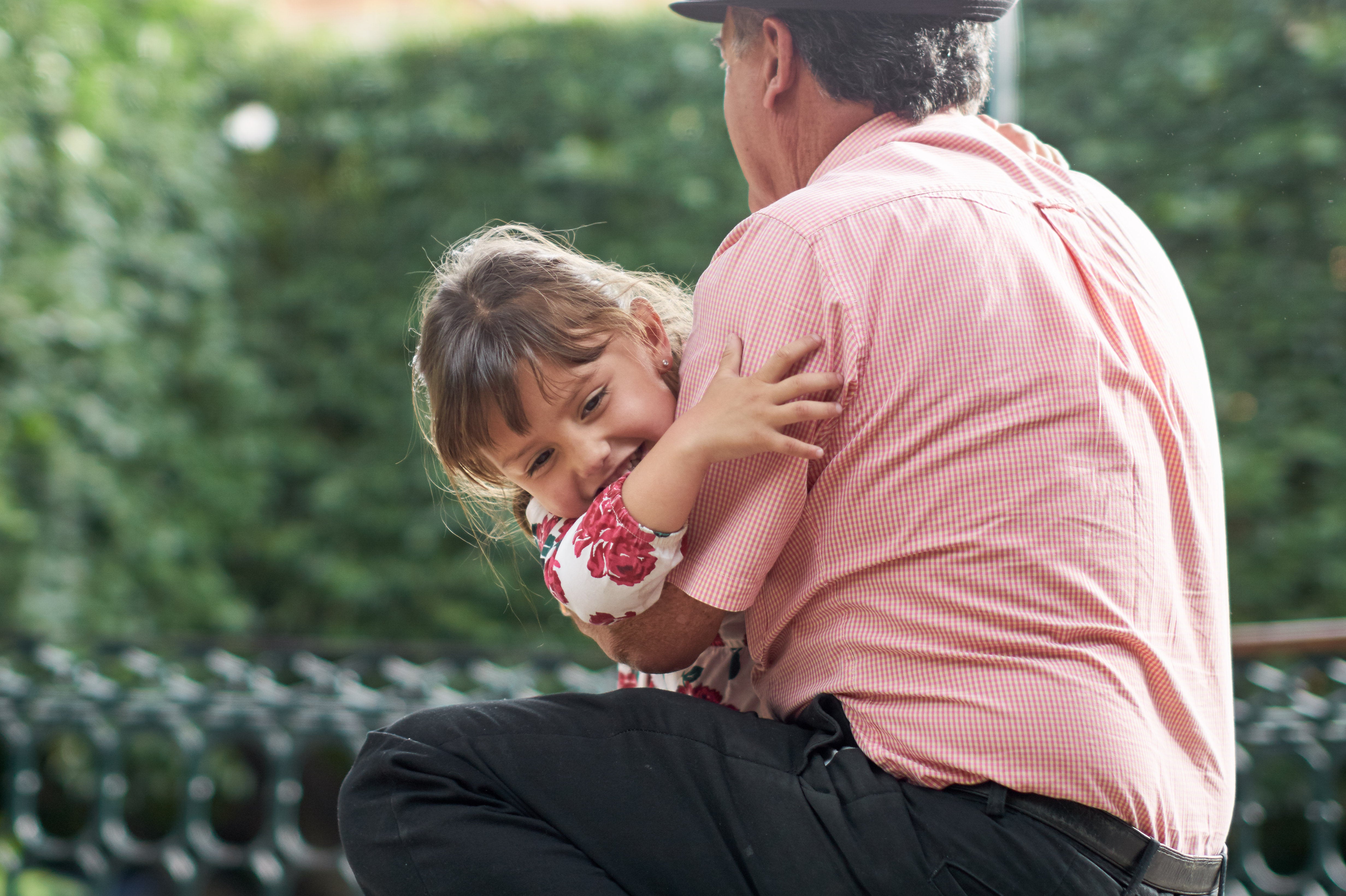 Little girl smiling while being hugged by her grandfather in the park