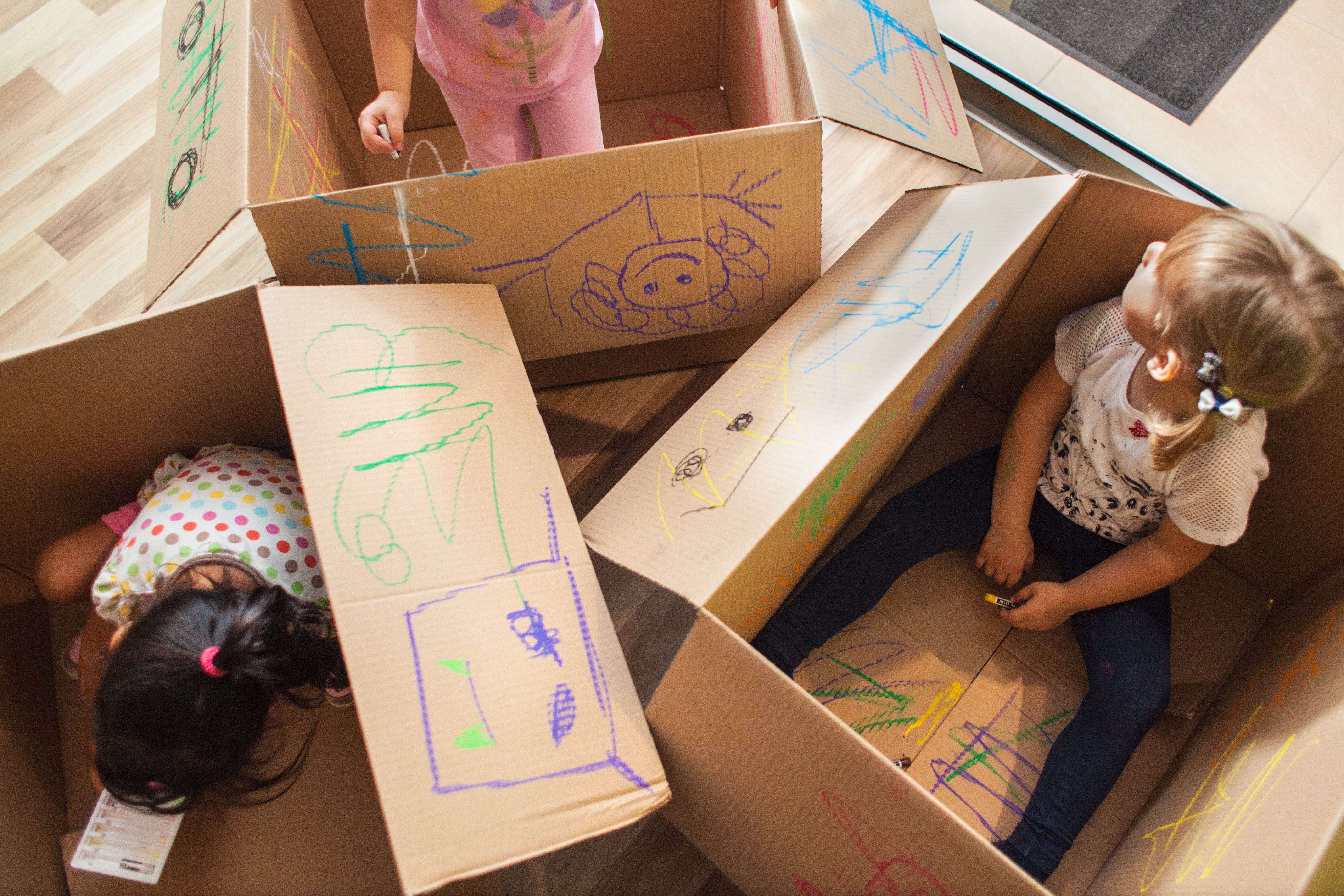 Several kids playing in boxes with crayons 