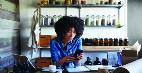 Young professional on cell phone while running shop business  