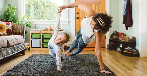  A mother and young daughter attempting the side plank yoga pose 