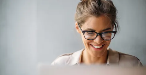 Close up of a woman with glasses working on computer.
