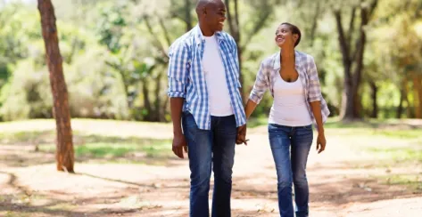 African American couple holding hands while walking in nature 