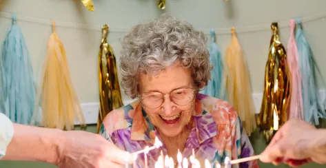 Older woman smiling in front of her birthday cake