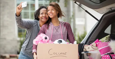Mom snaps a selfie with daughter as they load the car trunk with college supplies.