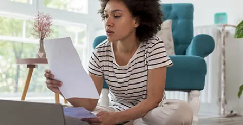 Beautiful woman sitting on the living room floor, calculating bank loan payout rates and paying household bills