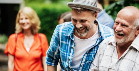 A man laughin and embracing with his father during a family barbecue.