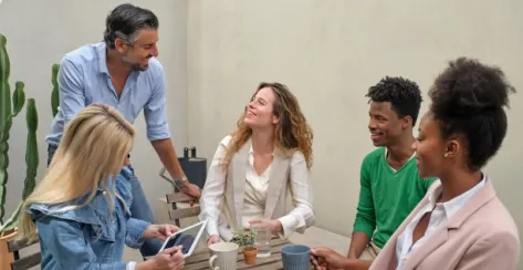 Diverse group of colleagues laughing in conversation while sitting down at a table. 