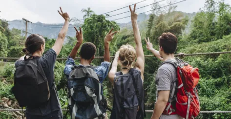 Young friends throwing up peace signs while gazing across scenery.