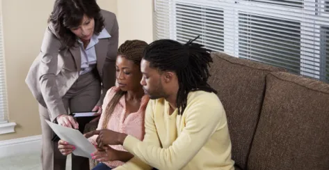 Insurance representative explains life insurance plans to a black couple.