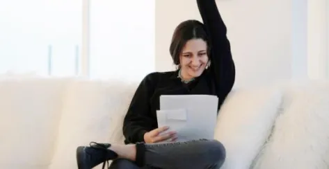 Excited woman looking celebratory while looking at financial documents.