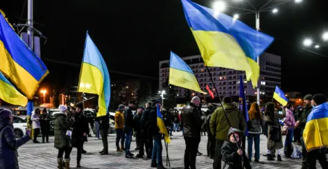 People gathered in the streets holding numerous Ukraine flags