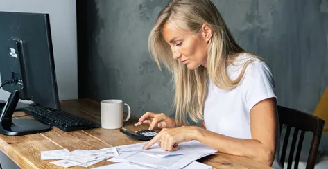 Young business woman sitting at a desk counts on a calculator bills and amounts. Financial literacy. Accounting and business.