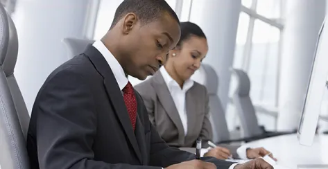 Young African American male and female sitting at a desk looking over paperwork