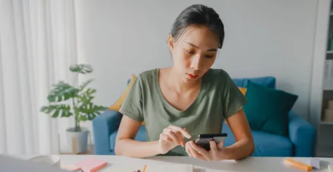 Worried asian female sitting down and scrolling through her mobile device.