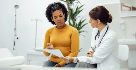 Young woman sitting at the doctor's office reviewing paperwork with a doctor. 