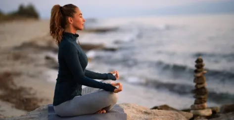 Profile of a woman with her eyes closed practicing yoga on a rocky beach by the sea